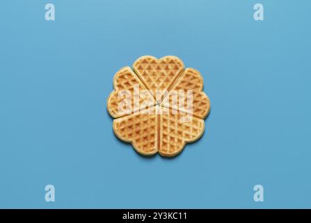 Vista dall'alto con waffle a forma di cuore minimalisti su sfondo blu Foto Stock