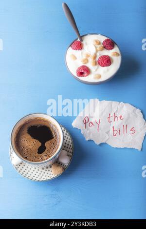 Colazione Leggera con un fresco e caffè arabo e una ciotola di yogurt con cereali e frutta e un pezzo di carta con il pagare le bollette messaggio, su un blu ta Foto Stock