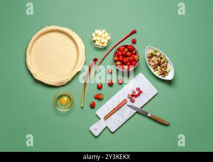 Vista dall'alto con gli ingredienti e l'impasto per un fruttato. Produzione di torta fatta in casa. Torta di fragole e rabarbarbaro Foto Stock