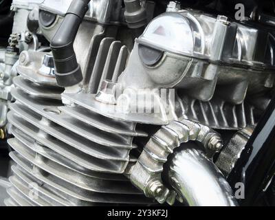Dettaglio ravvicinato del motore di una vecchia motocicletta d'epoca con telaio nero e tubi di scarico cromati lucidi Foto Stock