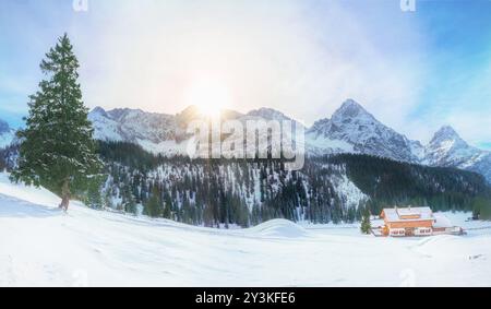 Vista panoramica di un villaggio alpino coperto di neve e circondato da alte cime delle Alpi e i loro sempreverdi foreste di abeti, situato in Foto Stock