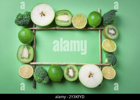 Frutta e verdura fresche a fette visualizzate in una cornice rettangolare su sfondo verde. Contesto di dieta. Disintossicazione degli alimenti. Sopra la vista con spazio di copia Foto Stock