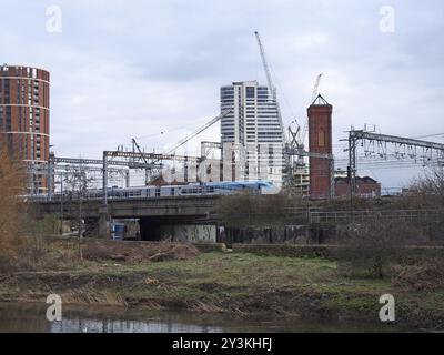 regno unito, 4 marzo 2020: Il fiume aire a leeds tratto dal sentiero che mostra la riva sud e holbeck con un treno sui binari ferroviari i Foto Stock