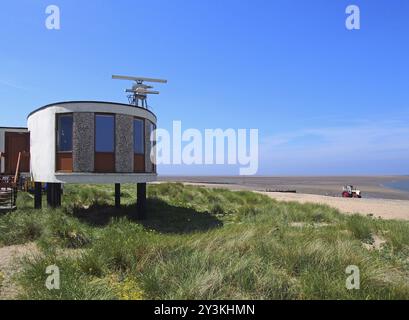 La vecchia brutalista stazione di guardia costiera di fleetwood con antenne radar con dune coperte di crasso che conducono alla spiaggia in una giornata estiva al sole Foto Stock