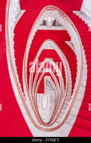 Scala a chiocciola realizzato in marmo e coperto con un tappeto rosso visto dal di sopra Foto Stock
