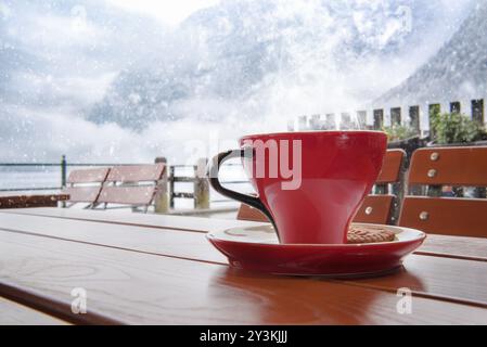 Momento di relax con una tazza di caffè caldo, su un tavolo in un ristorante austriaco, di Hallstatt, con una vista sui monti Dachstein, mentre al di fuori Foto Stock