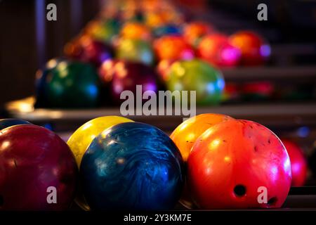 Molte palle da bowling preparate su un rack in una pista da bowling. Primo piano Foto Stock