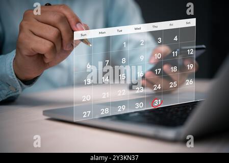 Primo piano di una persona che utilizza un calendario digitale su un notebook, evidenziando la data del 31 ottobre con un cerchio rosso, che indica la pianificazione o la pianificazione. Foto Stock