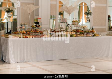 Elegante e lussuoso tavolo per banchetti con una squisita varietà di antipasti e arredi in un sontuoso ambiente. Foto Stock