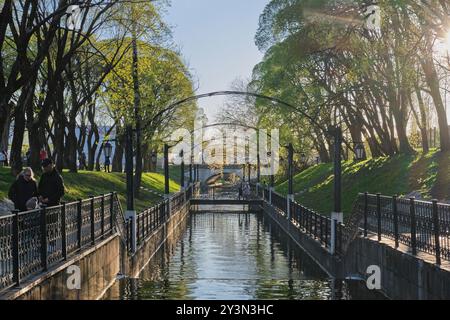 Perm, Russia - 18 maggio 2024: Fiume Motovilikha con sponde di cemento nel parco Garden of Eden, illuminato dal sole. Paesaggio primaverile della città Foto Stock