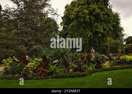 Un lussureggiante giardino caratterizzato da una varietà di fiori e piante colorate, tra cui grandi foglie e fogliame tropicale. La scena è ambientata su uno sfondo di Foto Stock