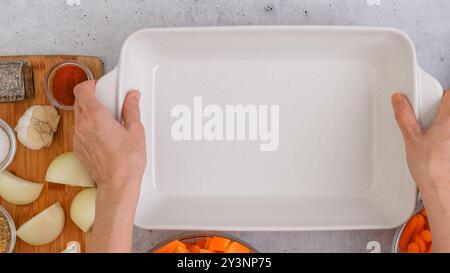 Ricetta per zuppa di zucca arrostita. Cubetti di zucca sbucciati e senza semi, carota, cipolla, aglio e spezie da vicino in una teglia da forno in ceramica inclusa nel kit Foto Stock