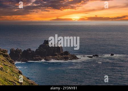 Uno splendido paesaggio costiero caratterizzato da scogliere rocciose e un oceano sereno al tramonto. Il cielo è dipinto con vivaci sfumature di arancione e viola, riflessi Foto Stock