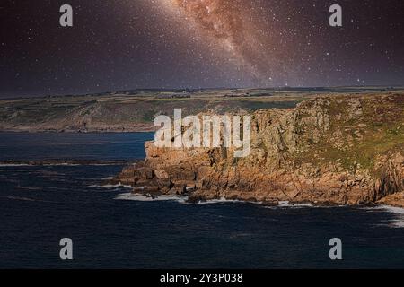 Uno splendido paesaggio costiero caratterizzato da aspre scogliere e un cielo stellato notturno con la via Lattea visibile sopra. Le onde oceaniche si schiantano contro la roccia Foto Stock