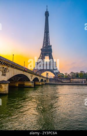 All'alba, la Torre Eiffel si erge maestosamente sopra la Senna, gettando riflessi sull'acqua mentre la città si sveglia con la luce soffusa del mattino. Foto Stock