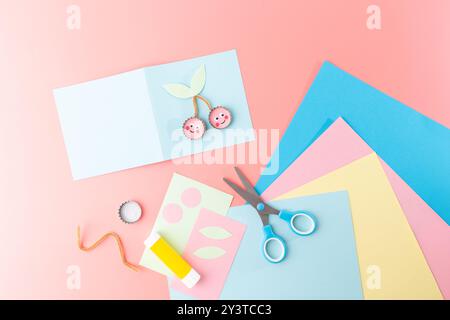 Progetto artigianale per bambini con forbici su carta con un modello di carta a tema ciliegio in blu. Ideale per attività fai da te e per l'apprendimento artistico , Foto Stock