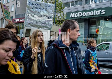 Di fronte a un ristorante McDonalds, un sostenitore dei diritti degli animali ha un cartello che dice "non puoi amare gli animali e mangiarli anche loro. Forza Vegan!". Attivisti e sostenitori dei diritti degli animali marciano per le strade di Varsavia per sensibilizzare sulle terribili sofferenze degli animali intrappolati nelle fabbriche e nell'agricoltura industriale. La marcia è indicata come un'opportunità per la comunità di unirsi e far sentire la propria voce, cantando sull'importanza dell'uguaglianza per gli animali. I partecipanti hanno iniziato la loro azione presso la statua di Copernico in Nowy Swiat Street. Marciarono con striscioni e cartelli verso il basso Foto Stock