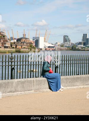 Una signora che si gode il sole del mattino presto, sul fiume Tamigi, a Greenwich, Londra, Regno Unito, Europa il venerdì, 13 settembre 2024. Foto Stock