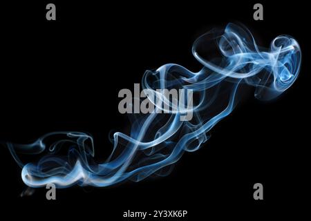 Il fumo blu etereo ruota elegantemente su uno sfondo nero profondo, illustrando fluidità, movimento e tranquillità in un'accattivante immagine astratta. Foto Stock