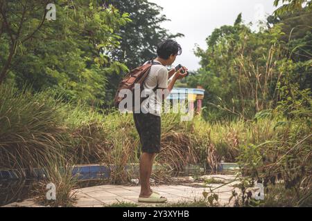 Giovani uomini che scattano foto con la fotocamera dslr. Ragazzo in piedi da solo nella natura selvaggia e a scattare foto Foto Stock