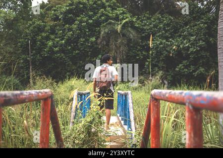 Zaino in spalla da solo che esplora luoghi abbandonati con zaino e macchina fotografica in mano. Gli uomini girano intorno su un ponte. Foto Stock