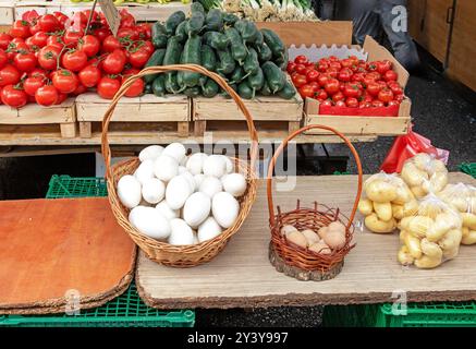 Uova d'oca bianche nel cestino di rattan con verdure fresche al banco del mercato Foto Stock