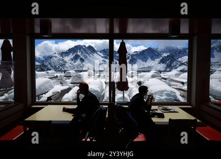 Oberstdorf, Germania. 15 settembre 2024. Gli escursionisti si siedono nel ristorante della stazione centrale di Fellhorn, alta 1780 metri, di fronte alla terrazza coperta di neve e al panorama delle Alpi. Ha nevicato una quantità insolitamente elevata per il periodo dell'anno nelle Alpi bavaresi. Crediti: Karl-Josef Hildenbrand/dpa/Alamy Live News Foto Stock