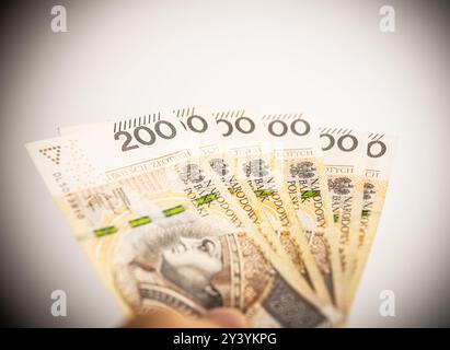 Una mano che tiene diverse banconote Zloty polacche, con una chiara visione di una banconota da duecento zloty, che enfatizza le transazioni monetarie e finanziarie in Foto Stock