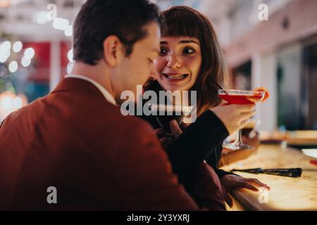 Una coppia felice si diverte con un drink in un accogliente ambiente bar Foto Stock