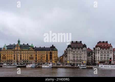 Stoccolma, Svezia. 16 aprile 2024 - edifici storici lungo il lungomare in una giornata nuvolosa Foto Stock