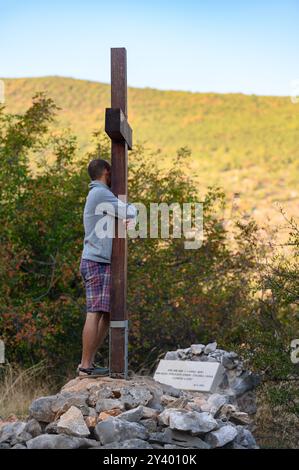 Un giovane che abbraccia la croce sul posto sul Monte Podbrdo a Medjugorje, dove la Vergine Maria ha dato il primo messaggio sulla pace per il mondo. Foto Stock