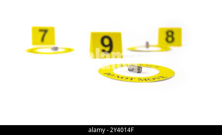 Un involucro di proiettile esaurito, posizionato all'interno di un cerchio giallo, etichettato con la prova del testo, non si muove, con un'etichetta sfocata numerata 9, 8 e 7, posta contro A. Foto Stock