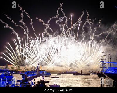 Il gigantesco spettacolo di fuochi d'artificio illumina il cielo notturno sull'acqua e diverse navi sono illuminate, Amburgo, Germania, Europa Foto Stock