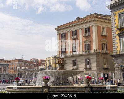 Vivace piazza cittadina con una grande fontana ed edifici storici sullo sfondo, napoli, mediterraneo, italia Foto Stock