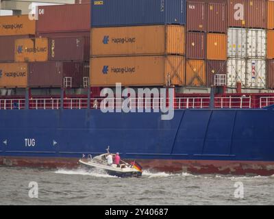 Una nave da carico con container Hapag-Lloyd al porto, una piccola barca con gente che passa, Amburgo, Germania, Europa Foto Stock