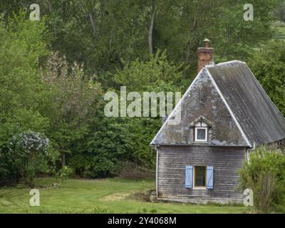 Casa rustica con persiane dipinte di blu, annidata nella natura verde e alberi alti, rouen, ITS, francia Foto Stock