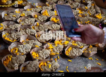 Un devoto sta fotografando un piccolo idolo di argilla di Lord Ganesha che sarà immerso nel fiume dopo la conclusione del festival Ganesh Chaturthi 2024. Questo atto simboleggia il ritorno della divinità ai cieli sul fiume Ping a Chiang mai, Thailandia. Ganesh Chaturthi è un festival dedicato a Lord Ganesha. Si ritiene che durante questo periodo, Ganesha discende per benedire i suoi devoti. Celebrato con grandi rituali in tutto il mondo, il festival si conclude con l'immersione degli idoli di argilla, simboleggiando che mentre la forma fisica si dissolve, la fede dura. Quest'anno segna la prima immersione a Ping Ri Foto Stock