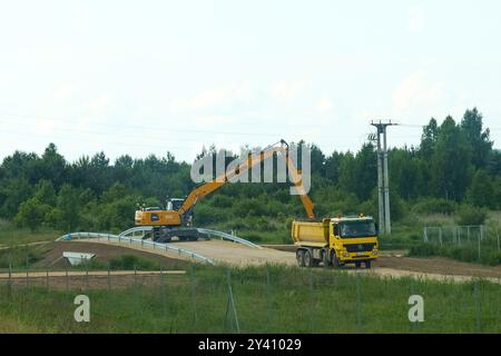 Gliwice, Polonia - 15 giugno 2023: I macchinari pesanti operano diligentemente su un progetto di costruzione, con un escavatore giallo e un camion a cassonetto che collaborano Foto Stock