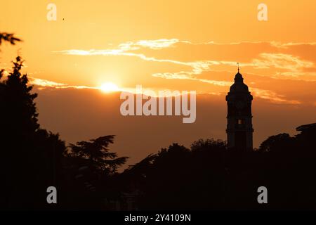 Vecchia torre orologio della stazione ferroviaria di Varna città, Bulgaria e uccelli volanti al tramonto Foto Stock