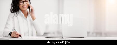 Donna latina parlando al telefono e la scrittura Foto Stock