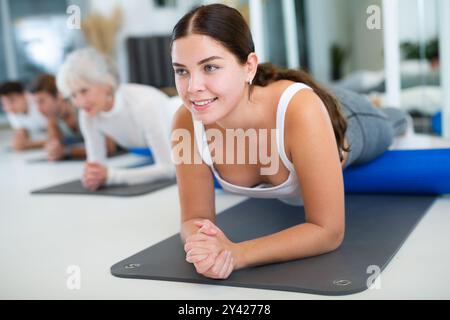 Donne e uomini che esercitano posizioni di yoga durante gli allenamenti di gruppo nel centro fitness, eseguendo stretching asana Urdhva Mukha Shvanasana Foto Stock