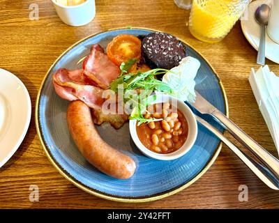 Colazione all'inglese tradizionale completa con salsiccia, uova, pancetta, patate, pomodori fagioli al forno e budino nero Foto Stock