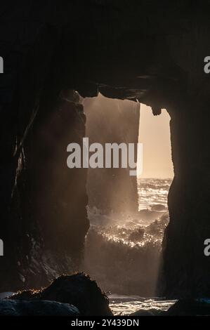 Particolare dell'arco Keyhole sulla spiaggia di Pfeiffer, con il sole che tramonta proprio dietro di essa. Foto Stock