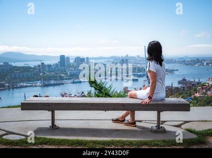 Donna russa di 50 anni che guarda il paesaggio di Vladivostok con vista sulla baia di Zolotoy, vista dal parco Nagorny, regione di Primorsky Foto Stock