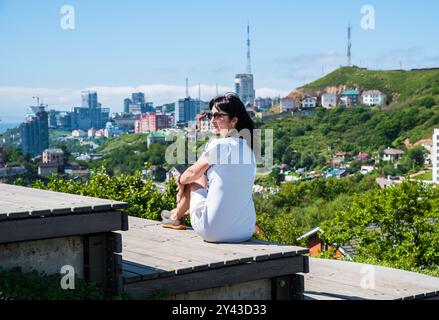 Donna russa di 50 anni che guarda il paesaggio di Vladivostok con vista sulla baia di Zolotoy, vista dal parco Nagorny, regione di Primorsky Foto Stock