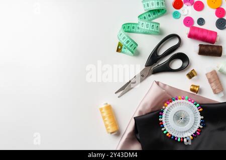 Elementi essenziali per cucire progetti visualizzati su un tavolo con tessuto, fili e strumenti Foto Stock