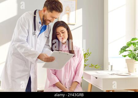 Medico di sesso maschile consulenza paziente di sesso femminile, condivisione dei risultati di laboratorio, visualizzazione delle cartelle cliniche Foto Stock