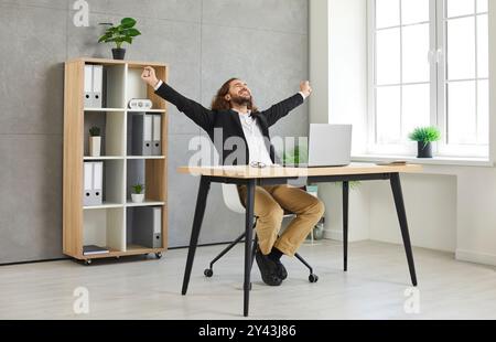 Felice uomo d'affari si rallegra del suo successo e alza i pugni in onore delle buone notizie. Foto Stock