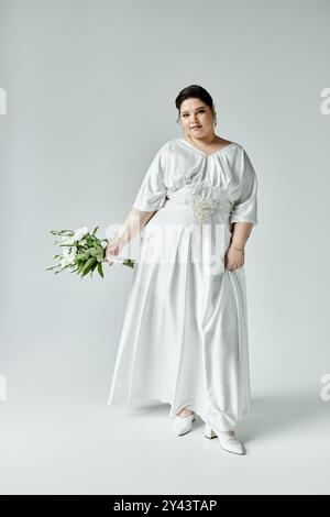 Una splendida sposa Plus size presenta il suo abito e gli accessori bianchi, incarnando eleganza e grazia. Foto Stock