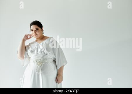 Una splendida sposa irradia fiducia e grazia in un abito da sposa bianco fluente con eleganti orecchini. Foto Stock